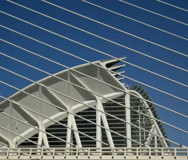 Una mirada geométrica al Museo de las Ciencias desde la estructura del Puente de l'Assut de l'Or. Fotografía de arquitectura en contrapicado donde las líneas diagonales de los cables de un puente atirantado crean un patrón rítmico sobre la fachada blanca