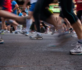 En las maratones que se celebran en diversas ciudades, una inmesa imagen baja de los corredores nos descubre un mundo paralelo de pies y deportivas. una bamba está inmovil y en conbtacto con el suelo, mientras un gran número de bambas, con sensación de movimiento la rodean.