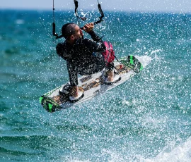 El Kitesurf es un deporte donde el deportista se coloca en una tabla de surf, que es traccionada mediante una cometa construida para tal fin. En la actualidad también es practicado sustituyendo la cometa por un parapente, lo que eleva su nivel de dificultad, por la necesidad de coordinación entre los dos practicantes involucrados. deportista practicando el Kitesurf, tabla de surf arrastrada por un parapente