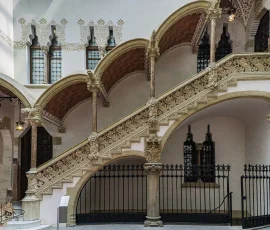 El vestíbulo se encuentra decorado con esgrafiados y azulejos, del que sobresale una escalera hacia la planta superior, labrada en piedra y adornada con motivos florales Escalera que lleva a la planta superior de la casa Macaya.