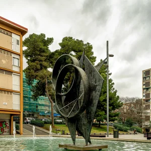 El barrio de Montbau se proyectó durante la década de los años cincuenta para dar cabida a la inmigración de la posguerra, que venía, principalmente, del sur de España. Inicialmente, el Patronato Municipal de Vivienda planificó 1.300 viviendas, que se doblarían en una segunda fase, a partir de 1961. El Pla de Montbau se concibió como el epicentro del nuevo vecindario. En el centro de la plaza se colocaron un estanque y una escultura de bronce de cuatro metros de altura. Obra del escultor Marcel Martí, lleva el nombre de Ritme i projecció (ritmo y proyección).arquitectura racionalista.