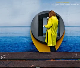 El mar también tiene un límite, aunque no lo veamos Persona usando un cajero automático bajo un mural azul que evoca el mar, en un día nublado
