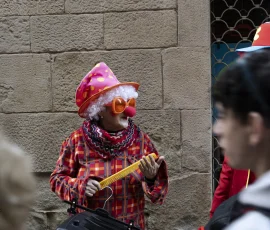 En medio del bullicio, cada mirada busca su propio sentido. Mujer con disfraz de payaso observando a un lado mientras la multitud pasa desenfocada.