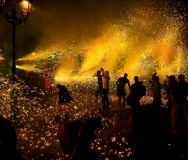 A los amantes de los fuegos artificiales, un correfoc es el mejor lugar donde pueden encontrarse. Gente saltando bajo las espurnas de fuegos artificiales.