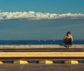 Siempre nos perdemos momentos únicos por no estar mirando lo que nos rodea, preferimos mirar un "cacharro" que nos roba la vida. Chica sentada al borde del mar mirando teléfono